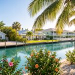 Ai-generated illustration of a canal lined with coastal cottages, docks and palms